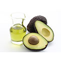  Whole and halved avocados with oil in a glass container.
