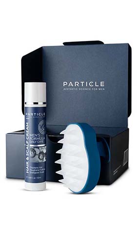 Particle brand men's grooming kit with hair cream and scalp massager against a dark blue box.